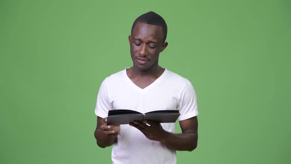 Young African Man Reading Book and Thinking