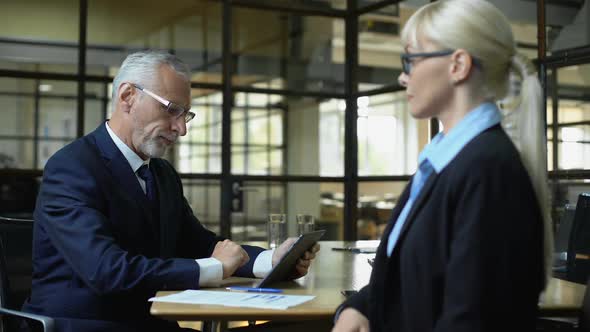 Senior Boss Praising Female Employee Shaking Hand, Using Business Tablet App