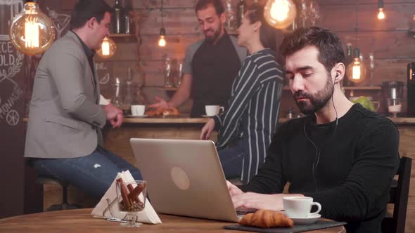 Bearded Handsome Man Working Very Enthusiastic in a Busy Coffee Shop