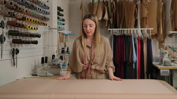 Close up of female tailor designer unwinding a big roll of fabric tissue on table at design studio