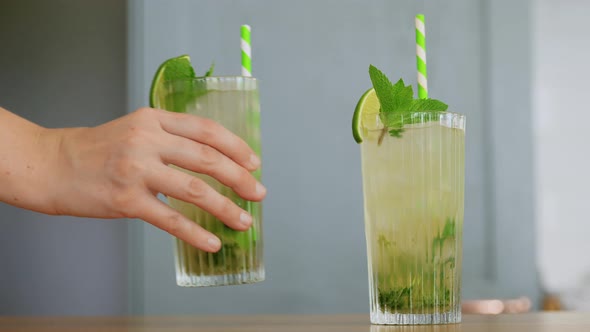 Hand Putting Glass of Mojito Cocktail on Table