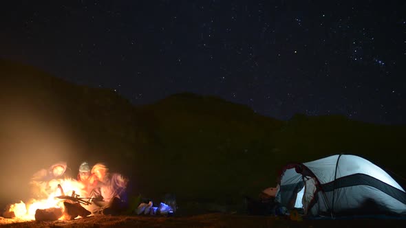 A campfire near a tent and campground at night.