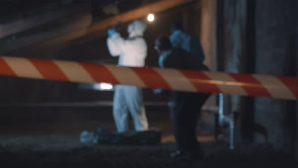 Two Policemen and Forensic Specialist Taking Photos of Evidence and Corpse on Crime Scene