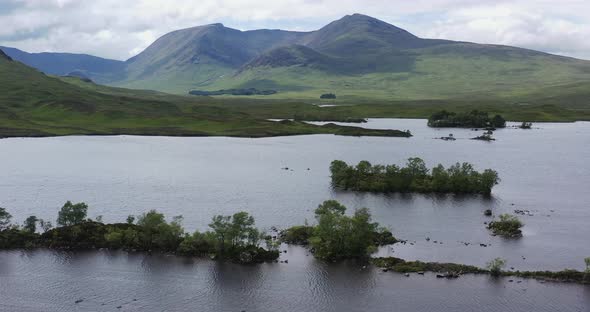 wooded islands on loch with mountains, Rannoch Moor, Highlands, Scotland, wide, aerial