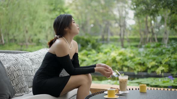 Cinematic View of a Beautiful Young Woman Having Coffee and Looking at Nature