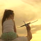 Little Daughter on Shoulders of Dad Is Playing with a Toy Airplane on the Field in Sun - VideoHive Item for Sale