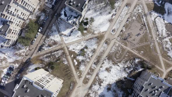 Flying Above Soviet Era District with Cars Parked Near Buildings in Early Snowy Spring in Vilnius