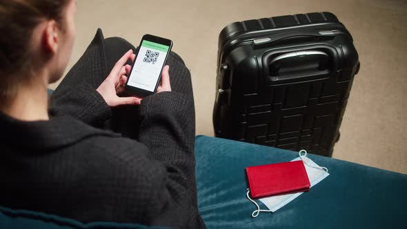 Woman Tourist Holding QR Code on Phone Sitting in Airport Terminal