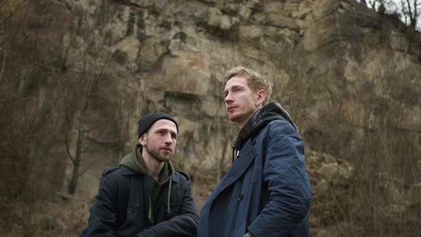 Two Friends In Nature. Stylish Young Guys. Behind Them Is Rock.