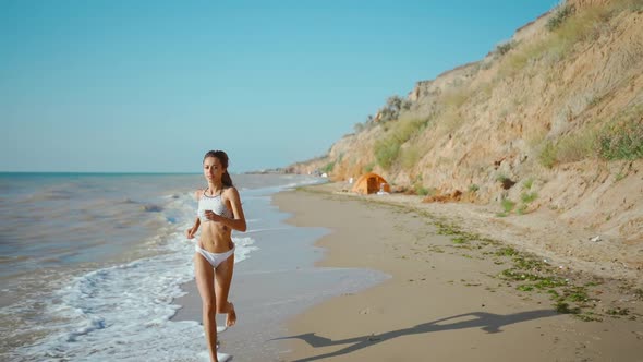 Young Fitness Woman in Bikini with Beautiful Slim Body is Engaged in Gymnastics at Sea at Sunrise