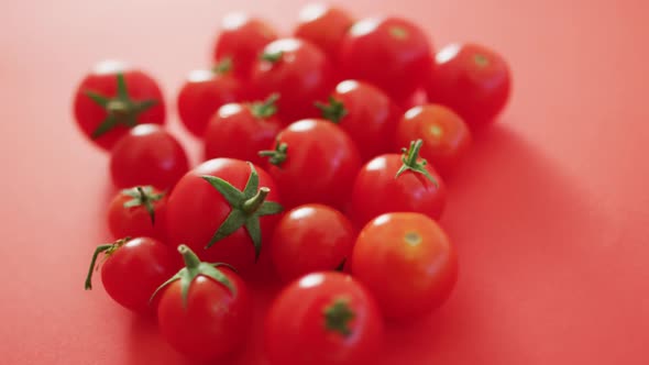 Video of close up of fresh red cherry tomatoes on pink background