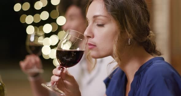 Woman Smelling Wine While Happy Talking and Toasting with Red Wine During a Romantic Gourmet Dinner