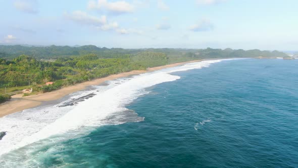 Calm ocean waves wash tropical beach on Asmara coast, East Java Indonesia aerial