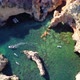 Drone shot of kayaks and boats passing in the ocean, people exploring caves and tunnels. - VideoHive Item for Sale