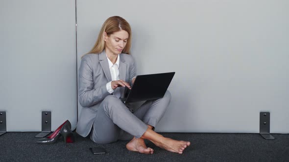 Stressed Young Woman Having Many Work Tasks Sitting on the Floor Without Shoes