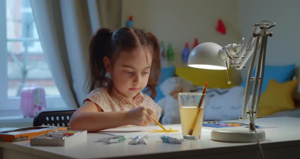 Cute Happy Little Girl Paints a Drawing with Watercolor Paints