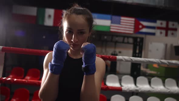 Closeup Shot of Confident Female Fighter with Wrapped Hands Looking at Camera While Posing in Gym
