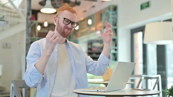 Redhead Man Having Loss on Laptop in Cafe