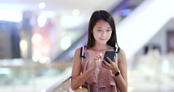 Woman use of mobile phone with the shopping mall background