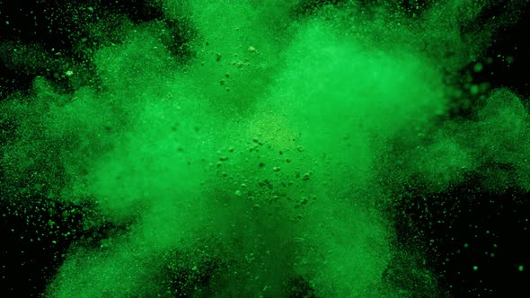 Colorful powder/particles fly after being exploded against black background. Slow Motion.