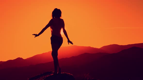 Female Silhouette Dancing at Beautiful Sunset on Mountain Background