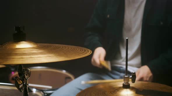 Drummer Playing the Drum Set in a Dark Room on a Black Background