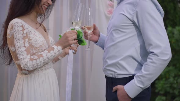 Side View of Unrecognizable Happy Groom and Bride Clinking Champagne Glasses at Wedding Altar