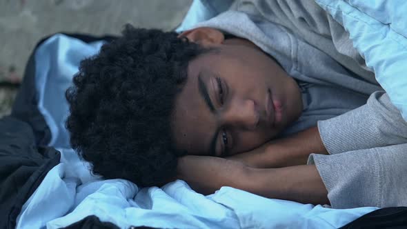 Homeless Afro-American teen boy sleeping on street