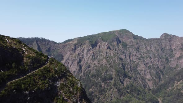 Aerial view of mountains on a sunny day with people watching it from a viewpoint.