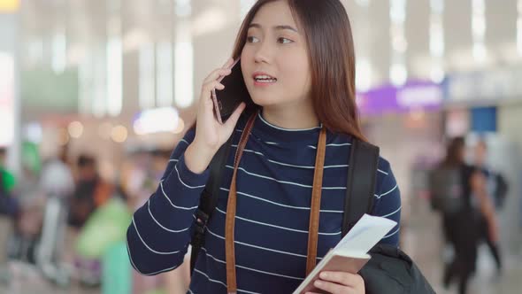 Young female traveler talking with smartphone to someone at airport