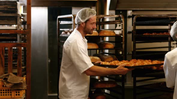 Bakers removing baked michetta from baking trolley