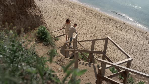 Carefree Couple Tourists Standing Wooden Ladder on Empty Seacoast Sunny Morning