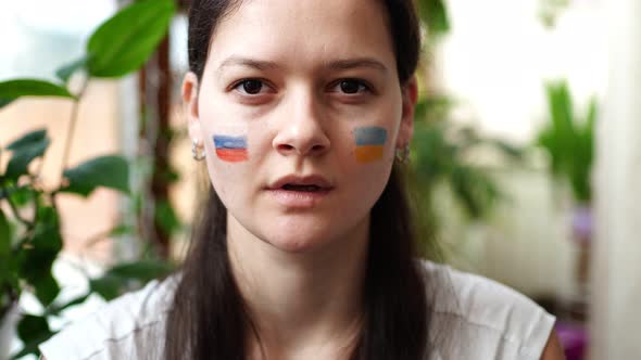 A Young RussianUkrainian Girl with the Flag of Ukraine and Russia on Her Face is Showing Keep