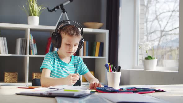 Boy is Doing  Homework at the Table. Cute Child is Learning at Home.