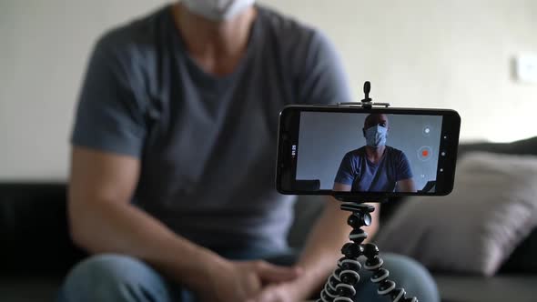 Bald Male Blogger in Medical Mask Recording Video Talking Using Smartphone