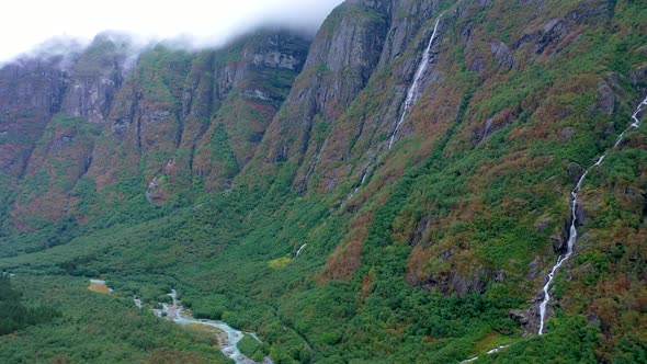 Paradise mountain landscape with green chain mountains with clouds and waterfall