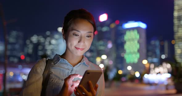 Woman use of smart phone in Hong Kong city at night