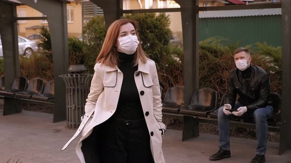 Closeup of a Girl in a Medical Mask and Gloves Catching a Taxi at a Bus Stop