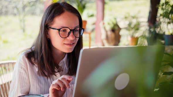 A Young Woman Freelancer Working on Her Laptop While Sitting on the Terrace