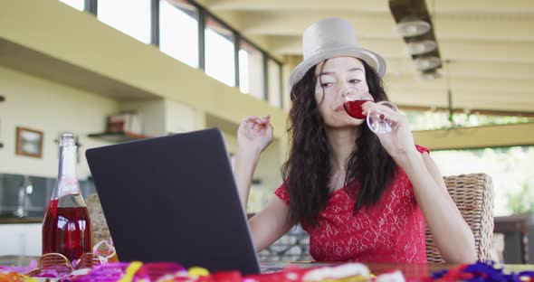 Happy biracial woman making new year video call, holding wine