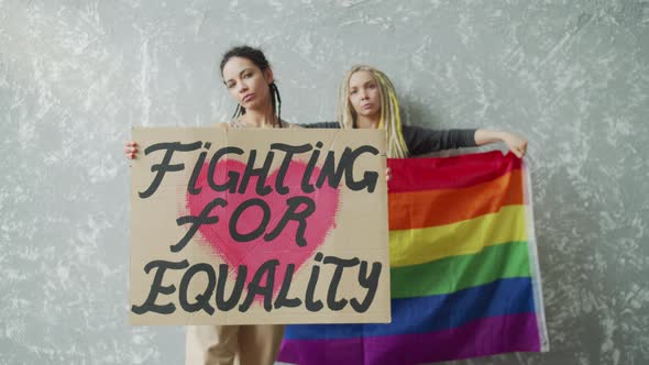 Teenagers are Standing By the Wall with LGBT Poster and Rainbow Flag