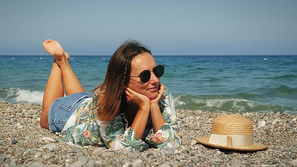 Young smiling female in sunglasses lying on beach