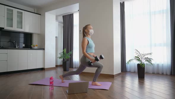 Strong Woman in Medical Mask Training with Dumbbells