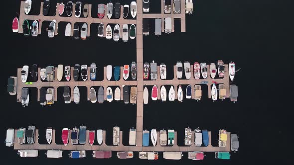 Overhead drone zoom-out shot of many boats docked in the marina at Payette Lake during sunset in McC