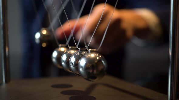 Cropped Shot of Businessman Pulling Ball of Newton Cradle