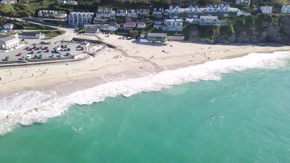 Turquoise Blue Water With Waves On Portreath Beach With Beachfront Hotels In Background During Summe