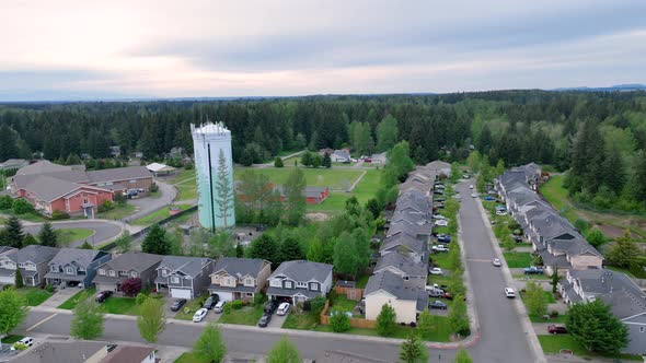 Orbiting drone shot around a suburban water tower with an elementary school in the background.