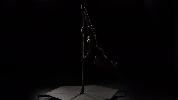 Girl Dancing a Dance on a Pylon. Black Background. Silhouette