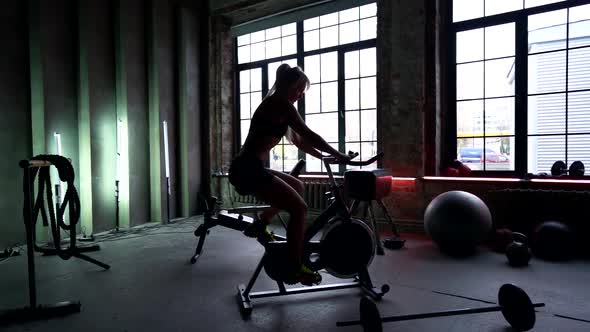 Sporty Woman Is Using Stationary Bike in Gym, Training Her Legs, Slender and Muscular Body, Healthy