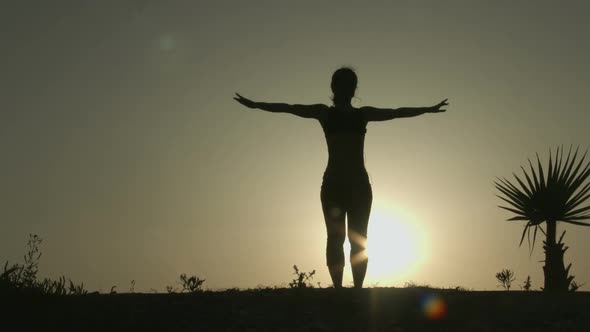 Silhouette of Woman Practicing Yoga in Rays of Sunrise. Balance of Body and Mind